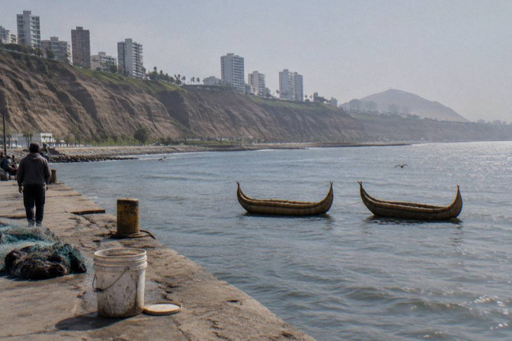 Reed boats floating on a wide highland lake with terraced hills behind