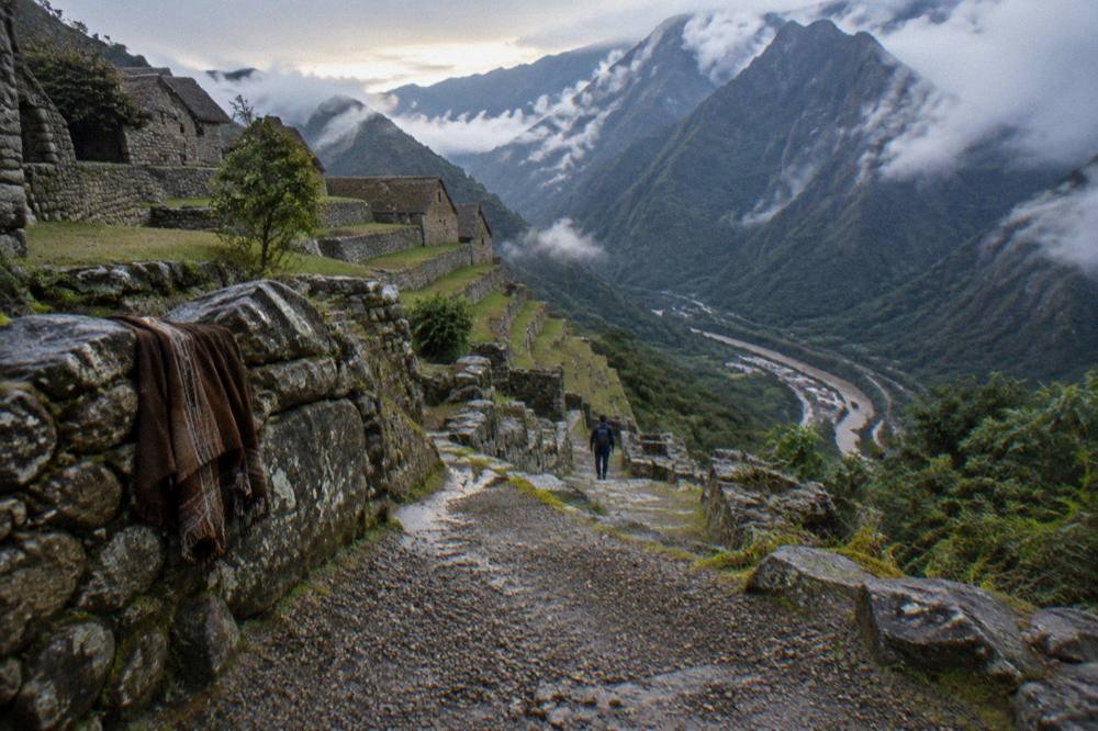 A stone terrace city set on a mountain ridge above a river valley in morning light