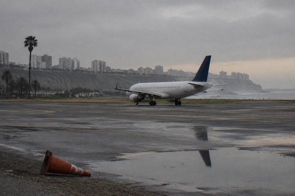 A passenger aircraft on the runway at Lima airport under an overcast sky