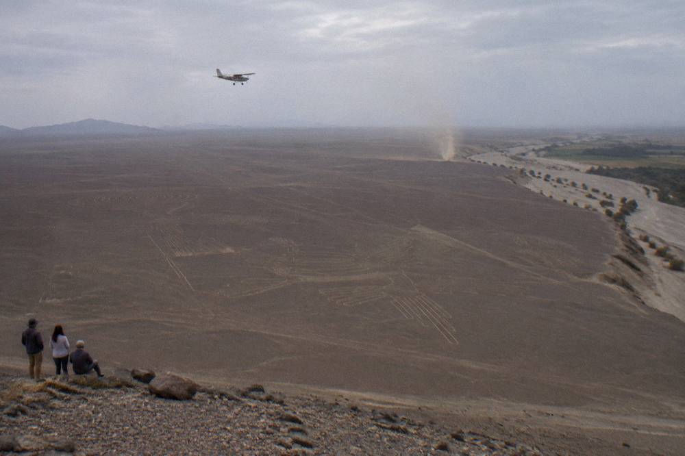A light aircraft flying over desert plains etched with ancient geometric line figures