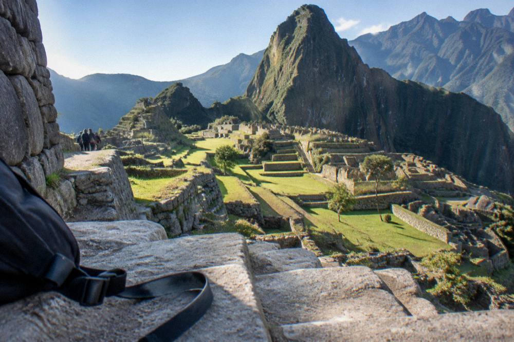 Inca terraces and stone walls of a mountain citadel under morning light with green ridges behind