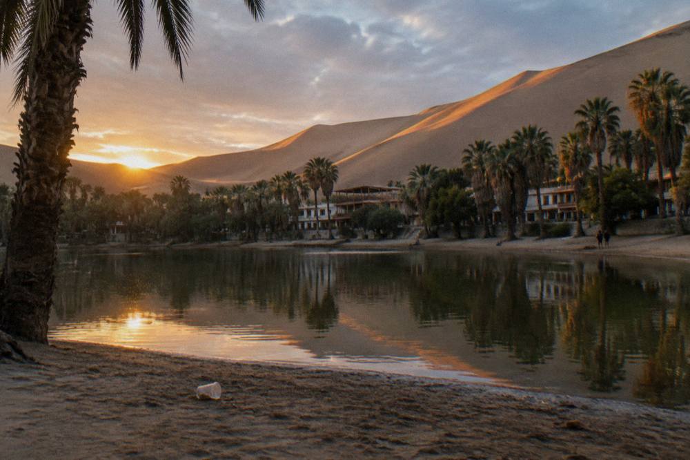 Oasis lagoon at Huacachina surrounded by sand dunes under a clear sky