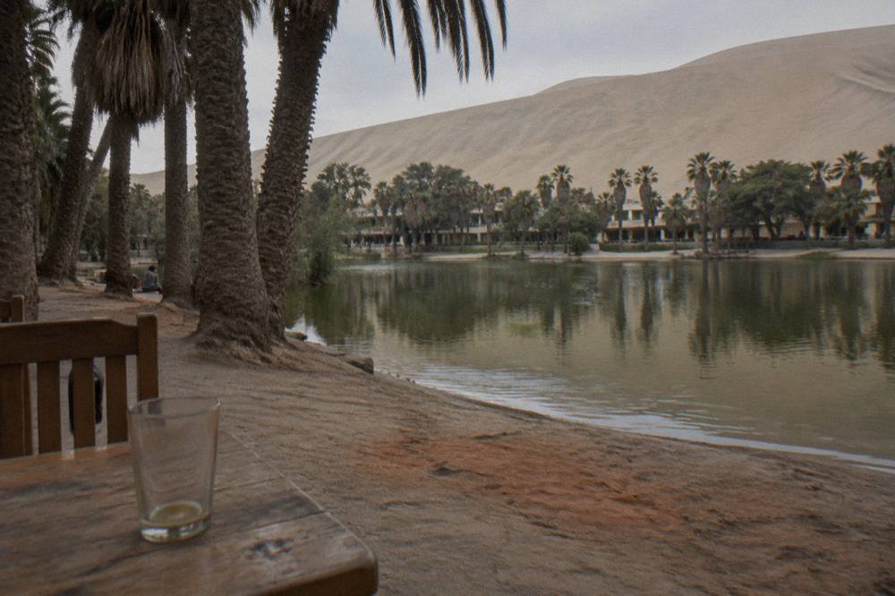 Oasis lagoon ringed by palm trees and sand dunes at Huacachina