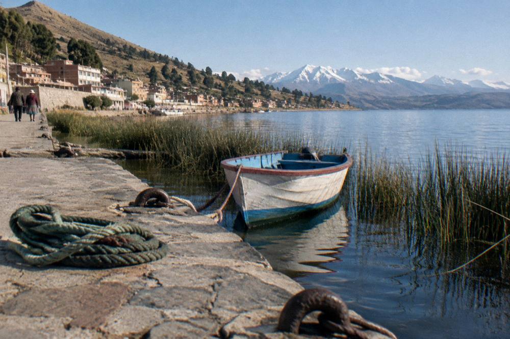 Deep blue lake with a boat and snow-capped mountains in the distance