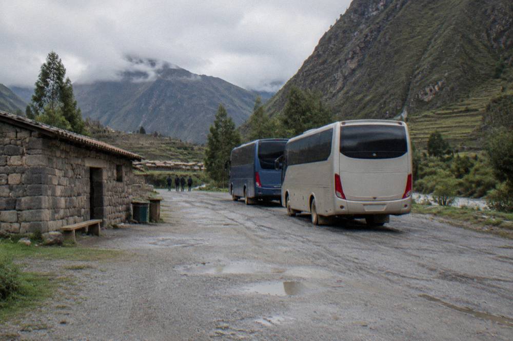 A rest stop beside the highway on the altiplano with a low stone building and parked buses under a wide blue sky