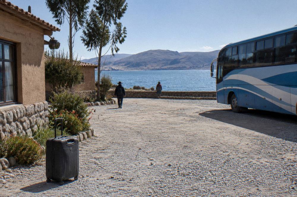 Morning light over Puno with Lake Titicaca in the background and a bus ready to depart from a hotel forecourt