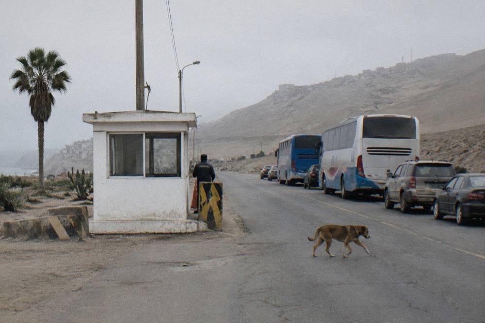 A quiet small border post building between bare altiplano hills with a short line of vehicles waiting