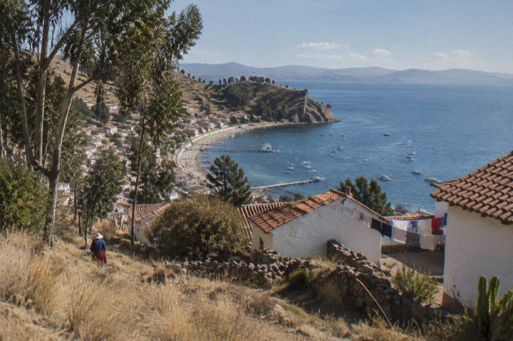 The lakeside town of Copacabana seen from a hillside with blue water and distant mountains across the bay